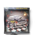 A square Chevrolet MDF wood wall clock in its shrink wrap packaging, featuring a classic 1967 black car with yellow flames on a checkered black and white background.