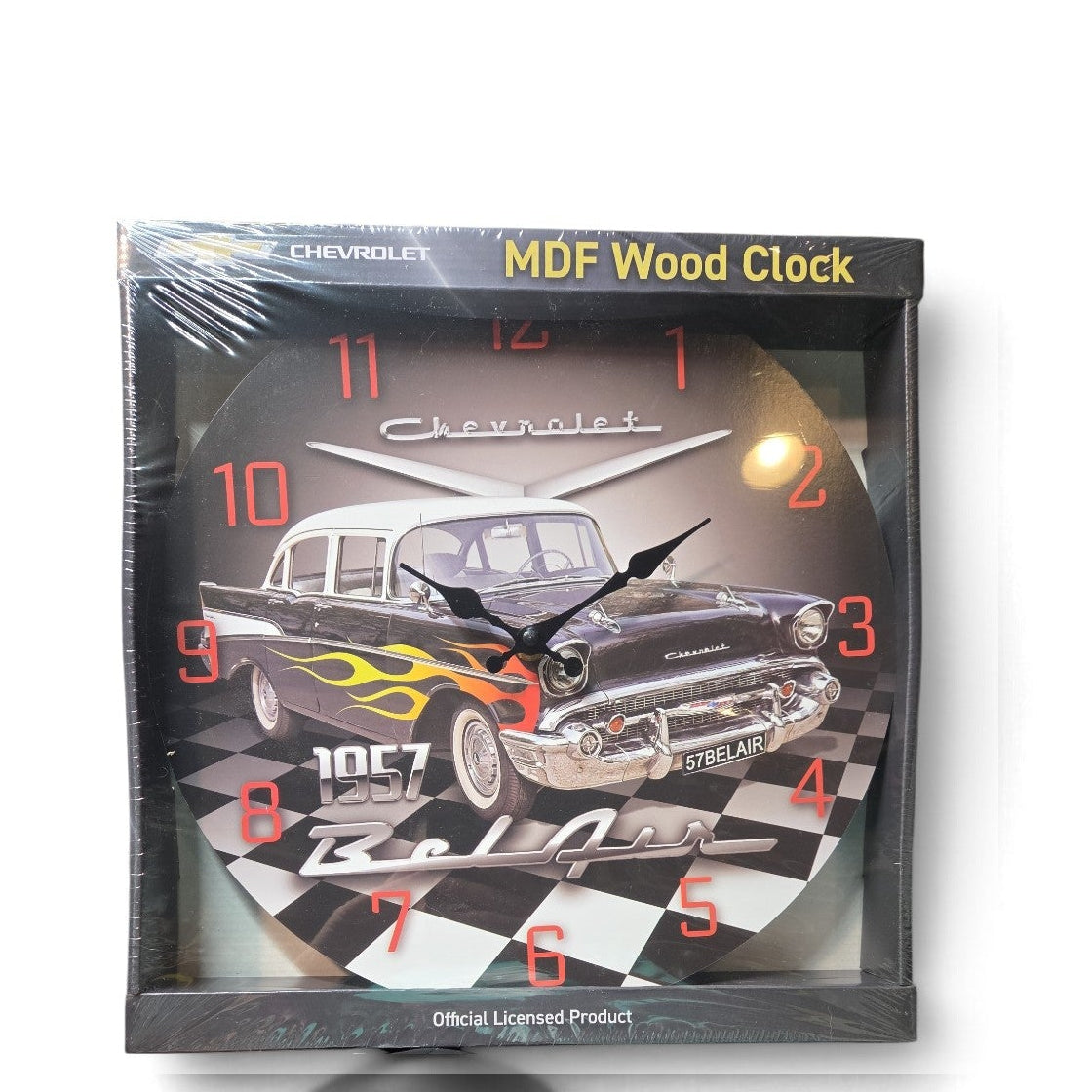 A square Chevrolet MDF wood wall clock in its shrink wrap packaging, featuring a classic 1967 black car with yellow flames on a checkered black and white background.